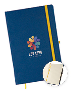Notebook amarelo aberto com papel pautado em um escritório, ao lado de um modem, um telefone e um copo de bebida.