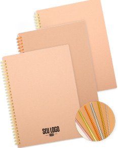 Caderno Kraft com design em papel kraft em branco, dentro de um envelope vazio de papelão. O notebook está aberto mostrando páginas em branco. Em volta, há outros objetos de papelaria e embalagens vazias.