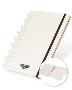 cade do disco ecológico com design vintage de cor marrom e amarela, feito de material reciclado. O caderno está aberto mostrando folhas em branco e uma caneta ao lado. No fundo, há um laptop e um livro, indicando um ambiente de escritório.